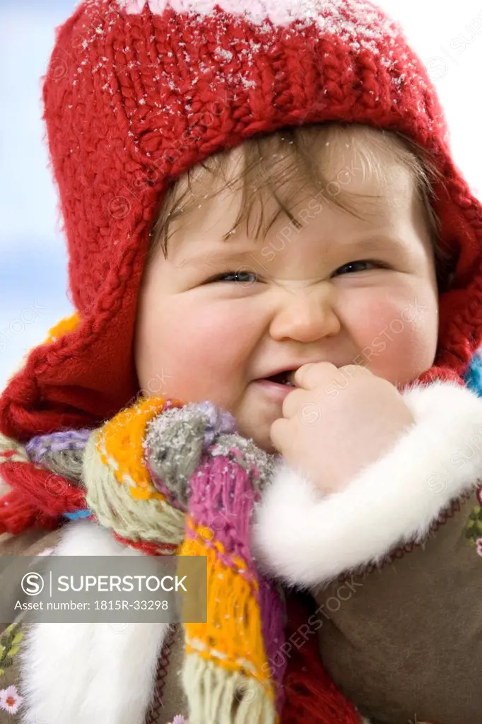 Baby girl (12-15 months) wearing cap, smiling, close-up