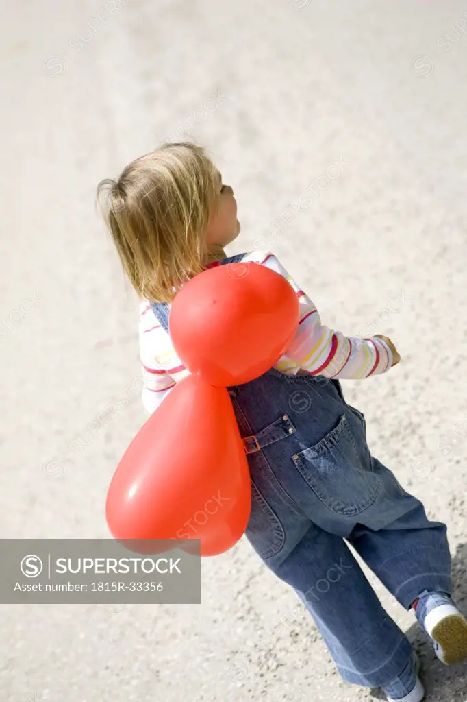 Girl ( 3-4 ) holding bunch of balloons, rear view