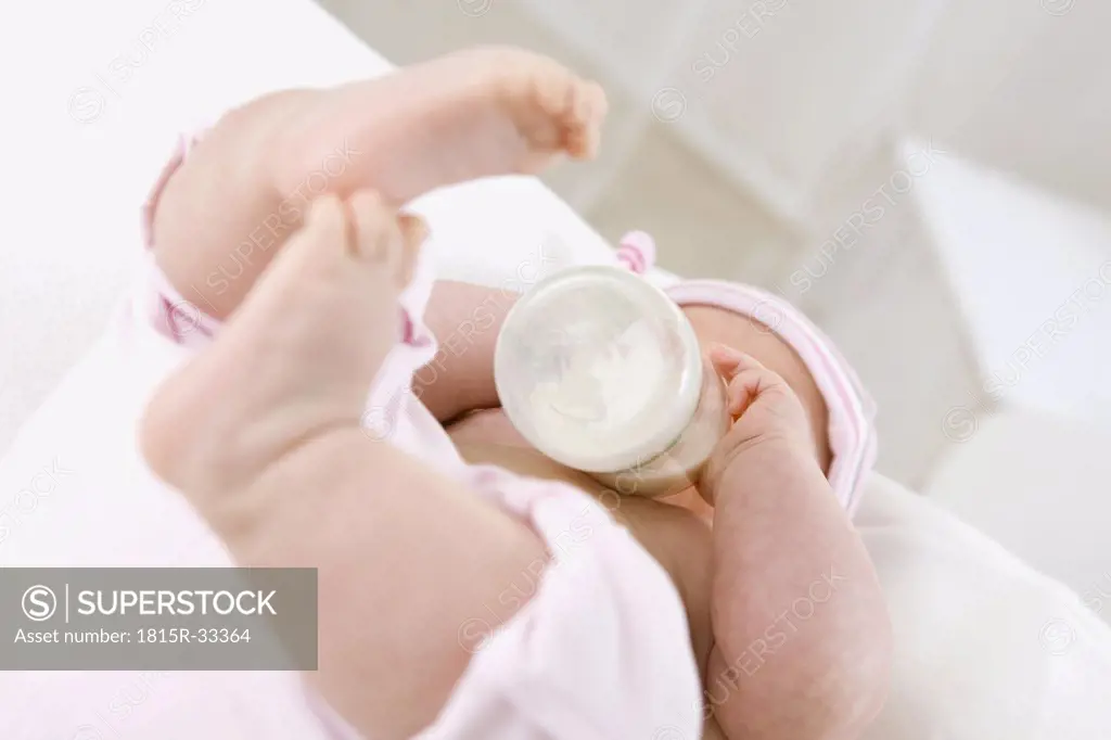 Baby girl (6-9 months) drinking milk from bottle, portrait