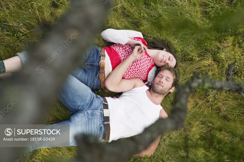 Young couple lying in meadow, eyes closed, elevated view