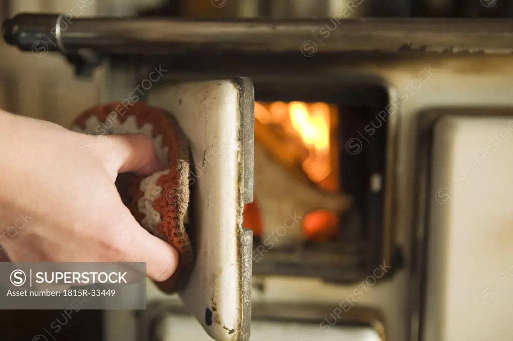 Woman opening wood stove, close-up