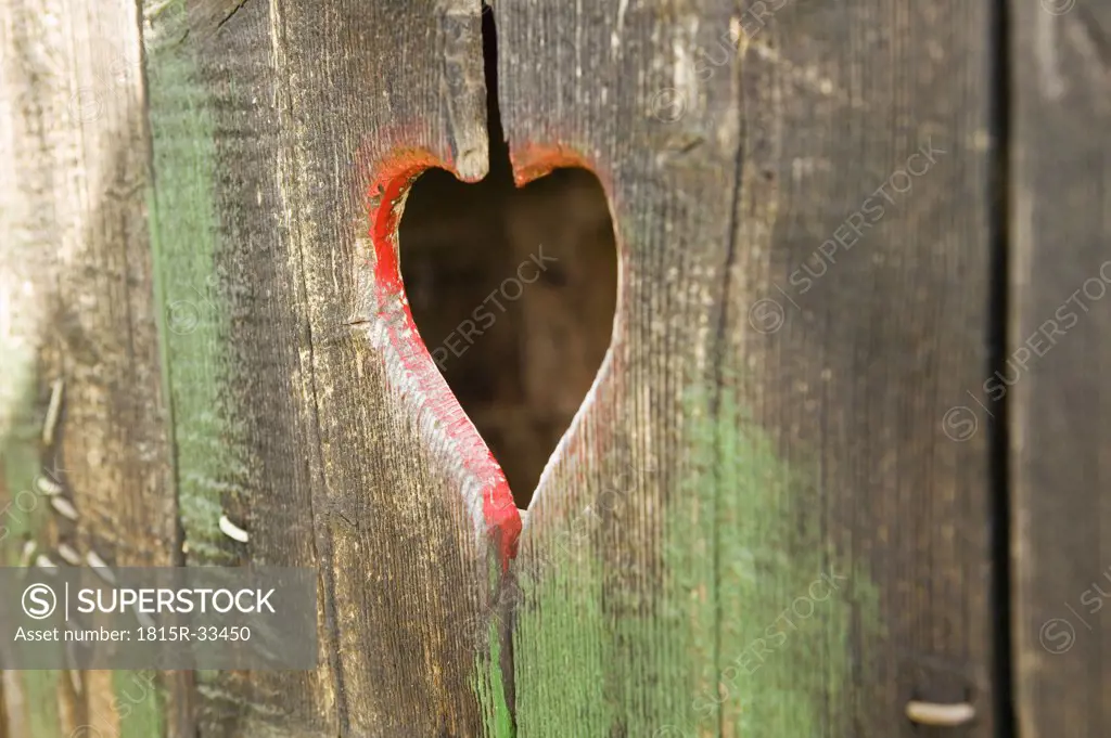 Wooden door with spyhole formed as heart shape, close-up