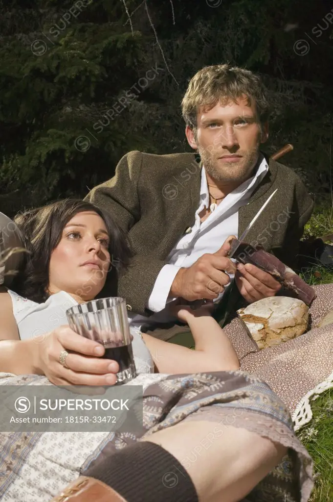 Young couple lying in meadow, having picnic