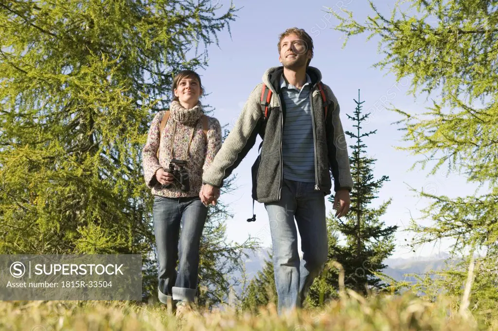 Young couple walking in meadow, hand in hand