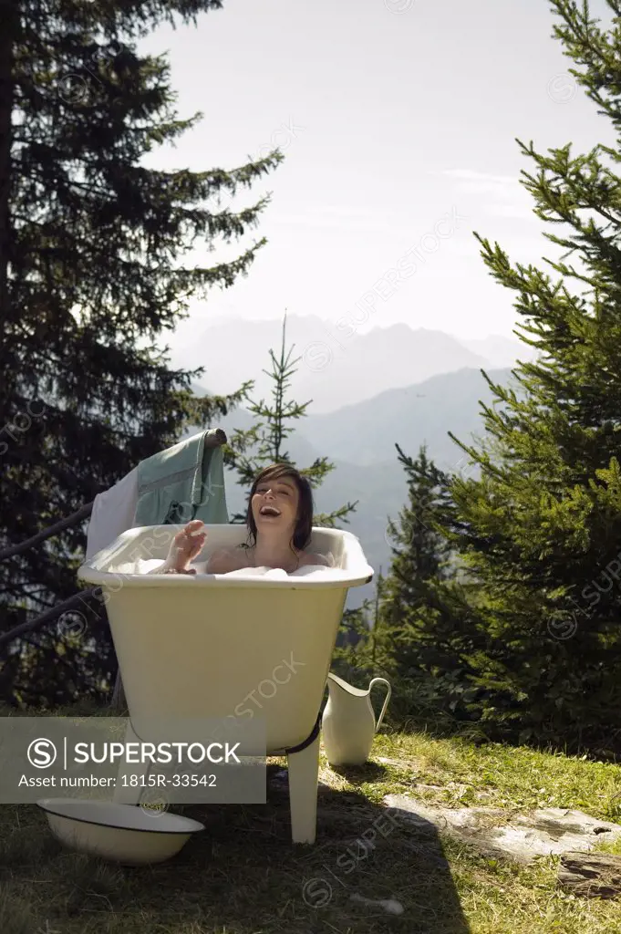 Young woman lying in bathtub, outdoors
