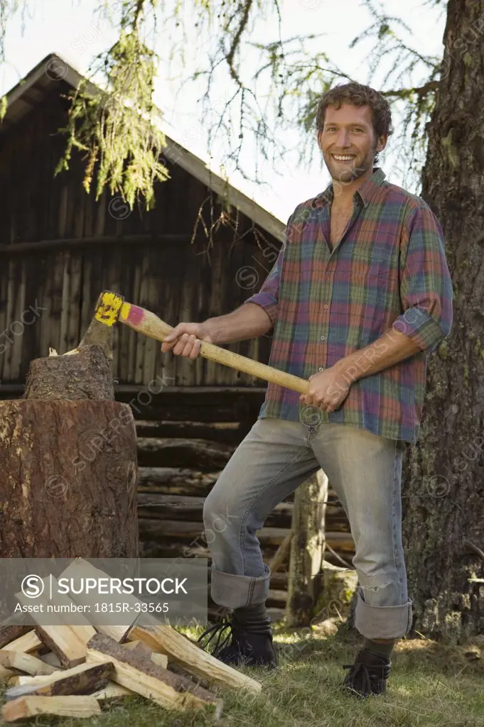Young man chopping wood, smiling