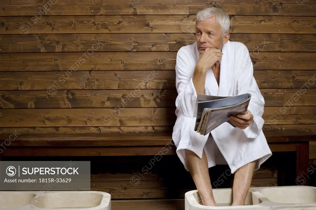 Germany, senior man having foot bath in health spa