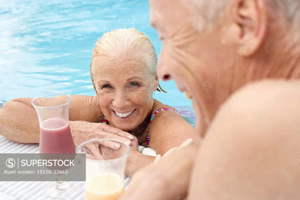 Germany, senior couple drinking cocktail at pool