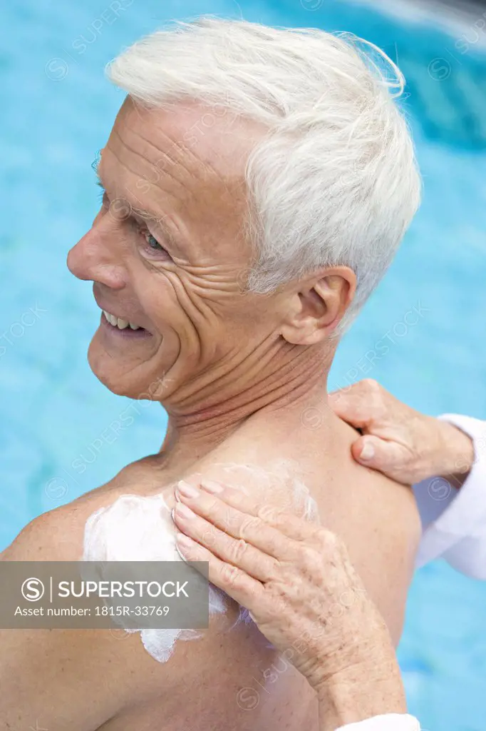 Germany, woman applying sunscreen on man's back, close-up