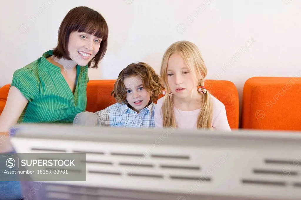 Mother and children watching television together