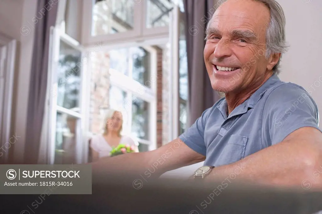 Senior man sitting at table, smiling, portrait