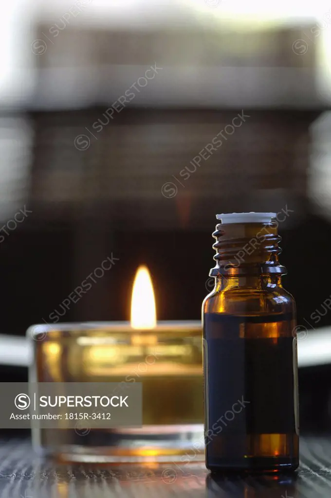 Bottle of scented oil, beside a tealight, close-up