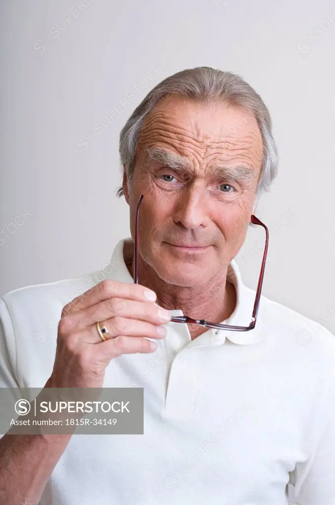 Senior man holding glasses, portrait