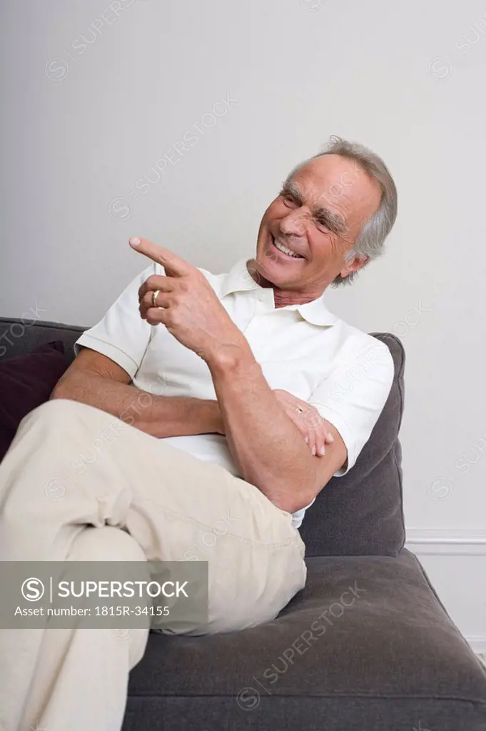 Senior man on sofa, smiling, portrait