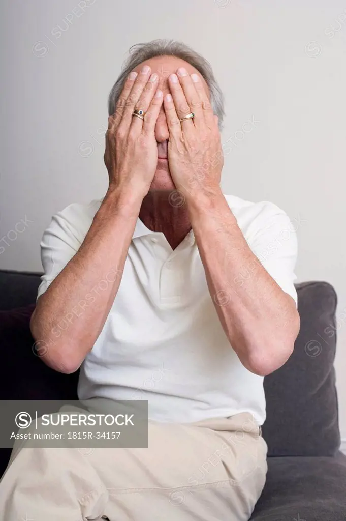 Senior man covering face with hands, portrait