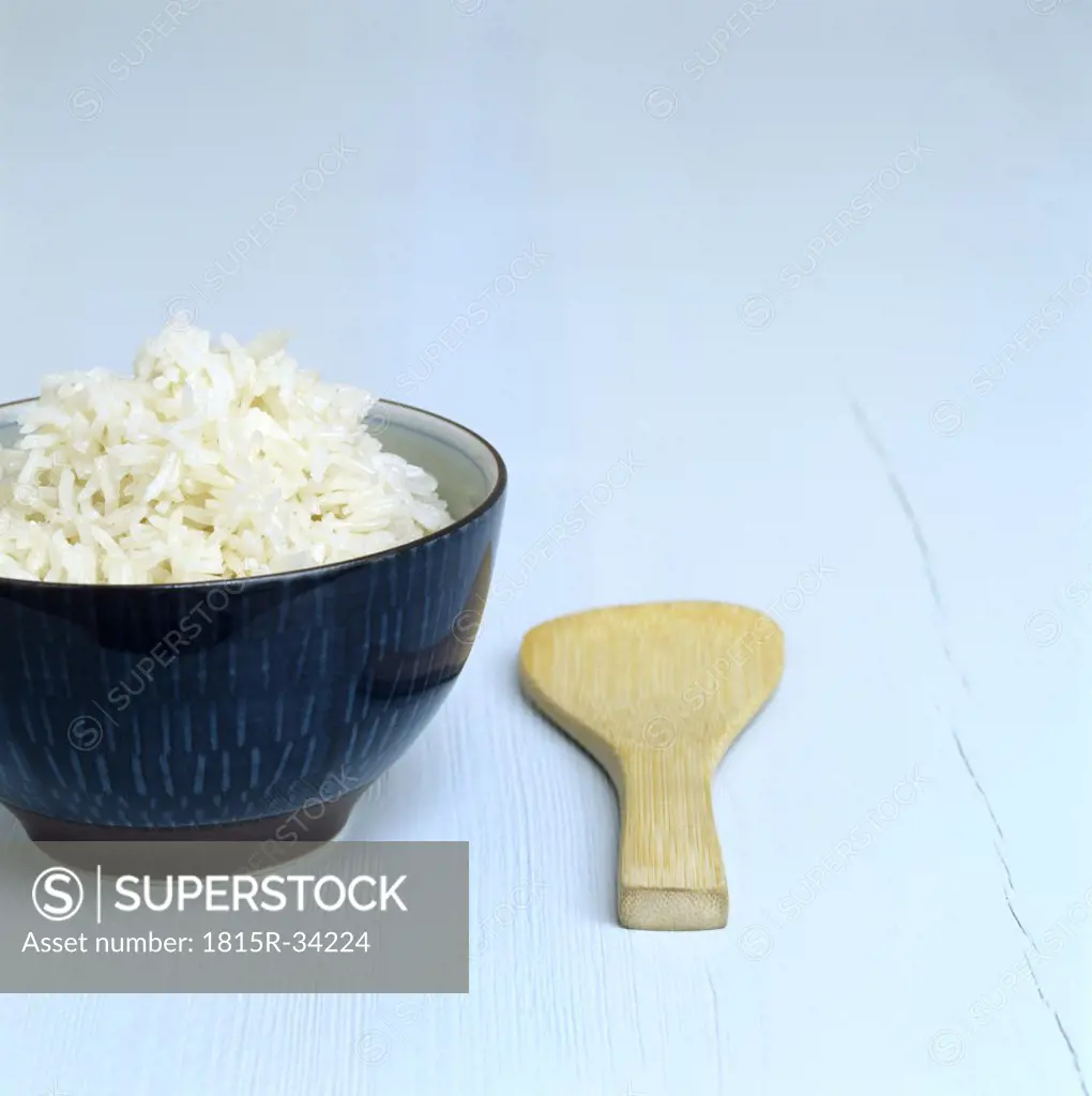 Cooked rice in a dish, wooden spoon aside