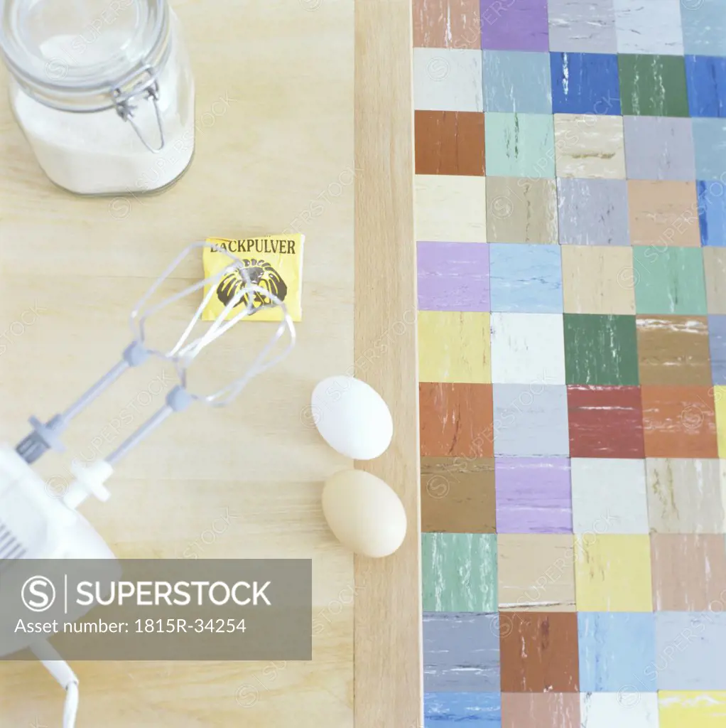 Electric mixer, eggs, flour and baking powder on kitchen table