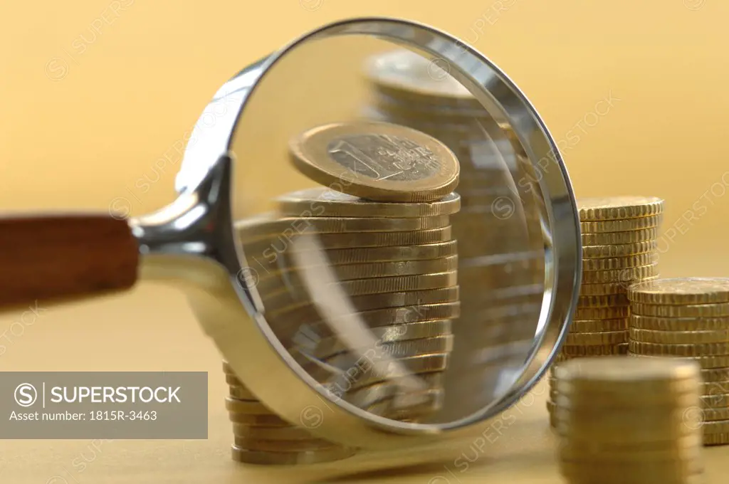 Euro coins under magnifying glass, close-up - SuperStock