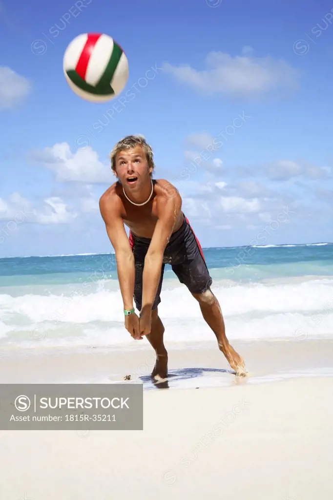 Young man playing volley ball on beach