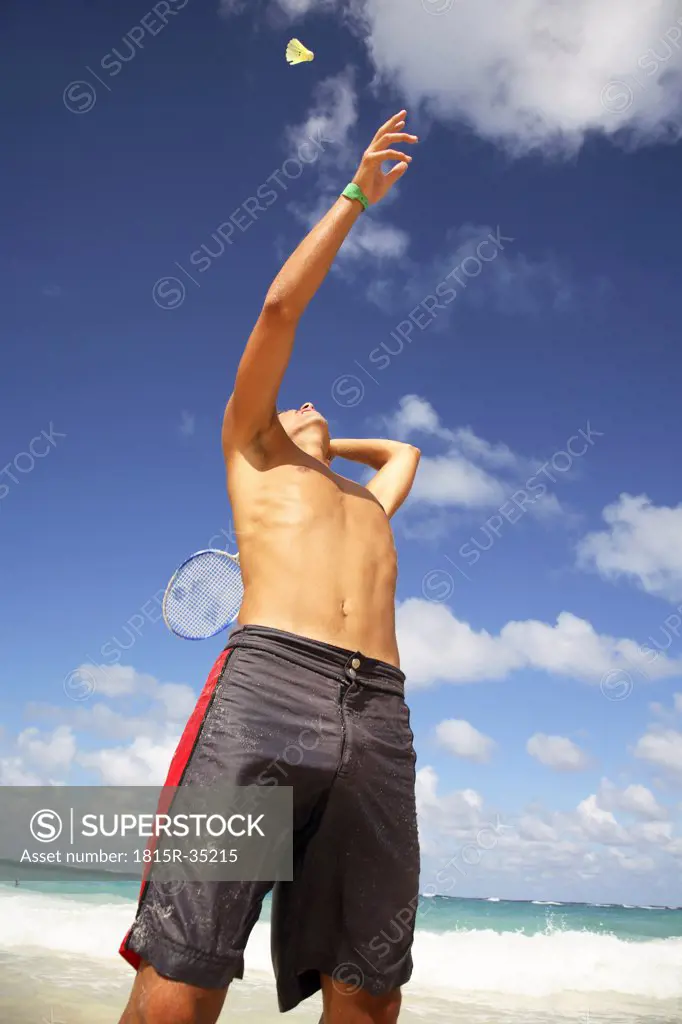 Young man playing batminton on beach