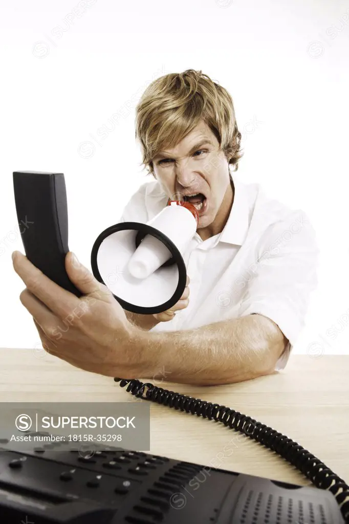Man holding phone, shouting in megaphone