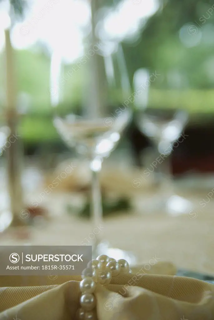 Napkin with pearls, wine glasses in the background