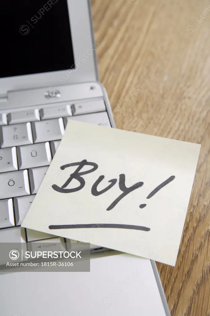 Adhesive note on laptop saying ""Buy""