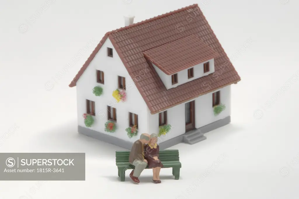 Plastic figurines sitting on bench of toy house