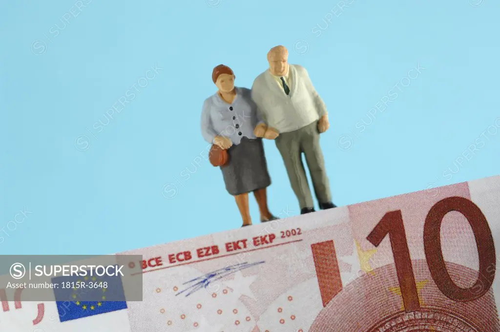 Plastic figurines standing on banknote