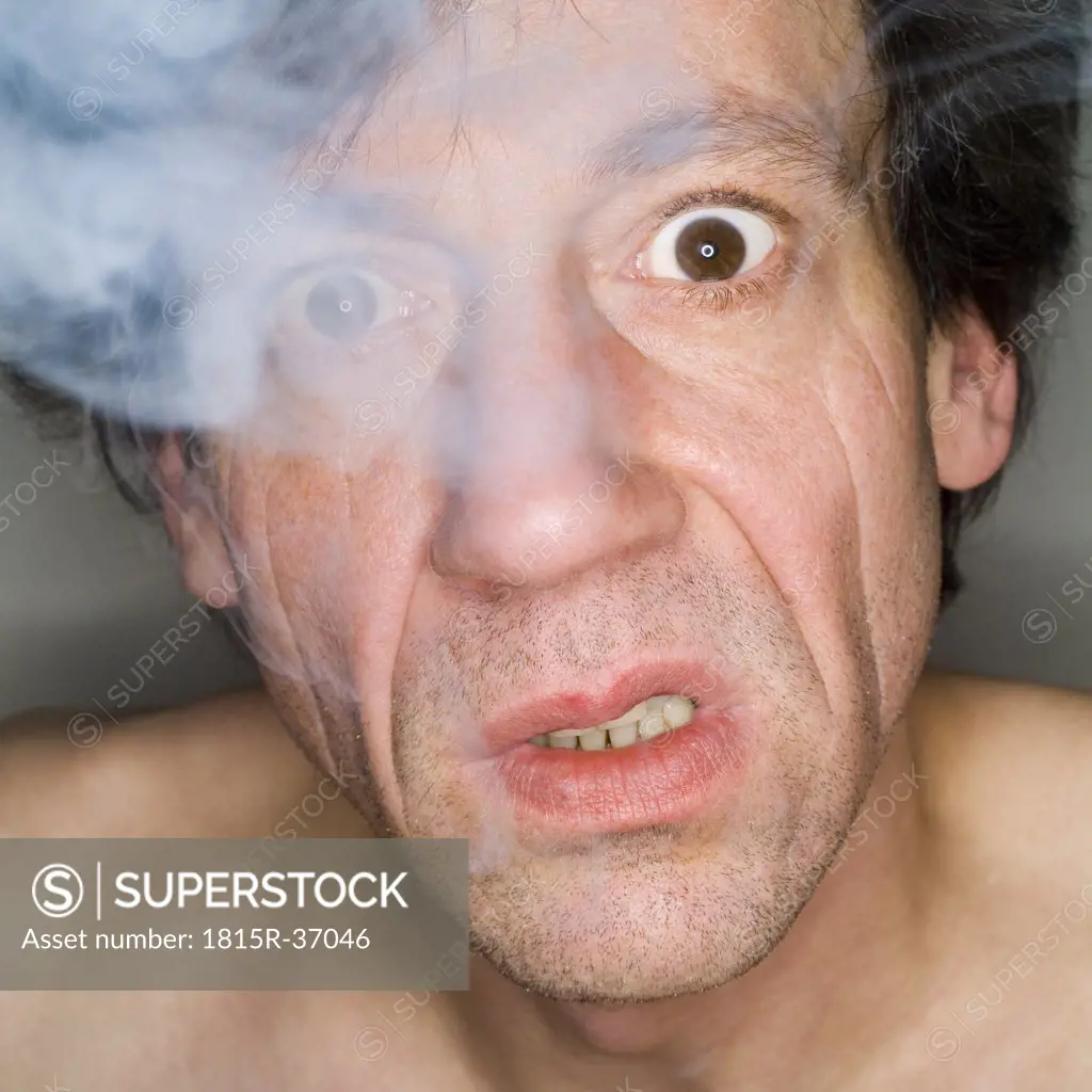 Man exhaling cigarette smoke, close-up, portrait