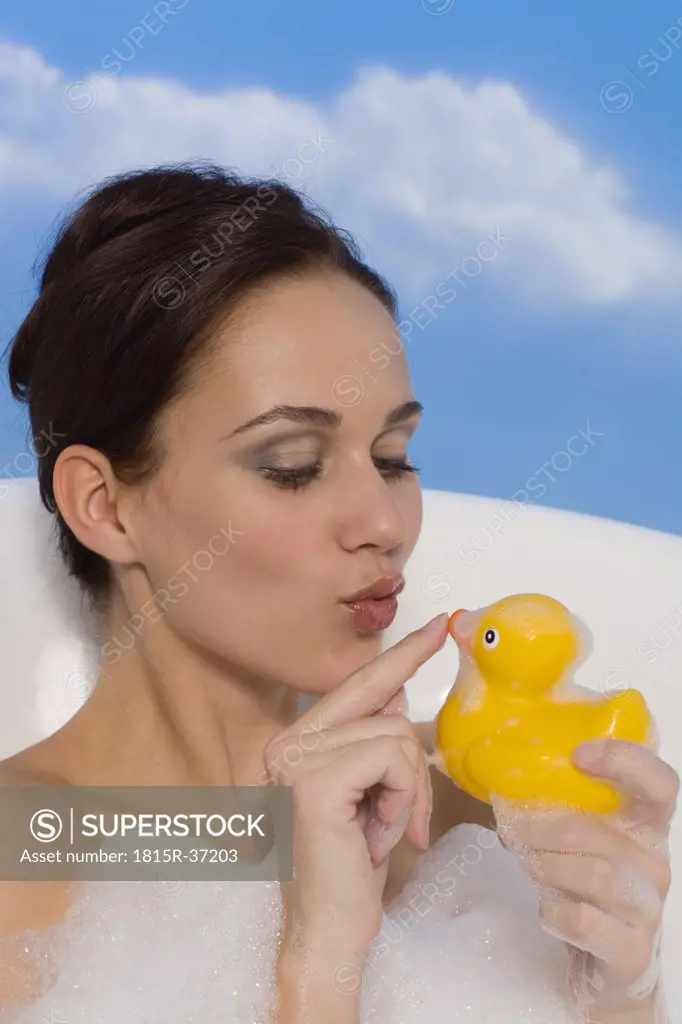 Young woman in bath holding rubber Duck, portrait