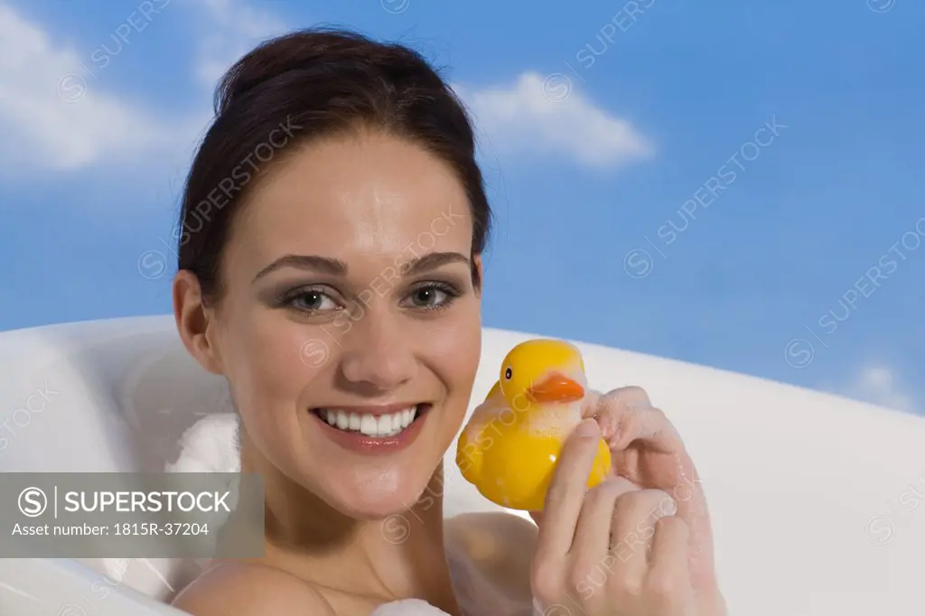 Young woman in bath holding rubber Duck, portrait