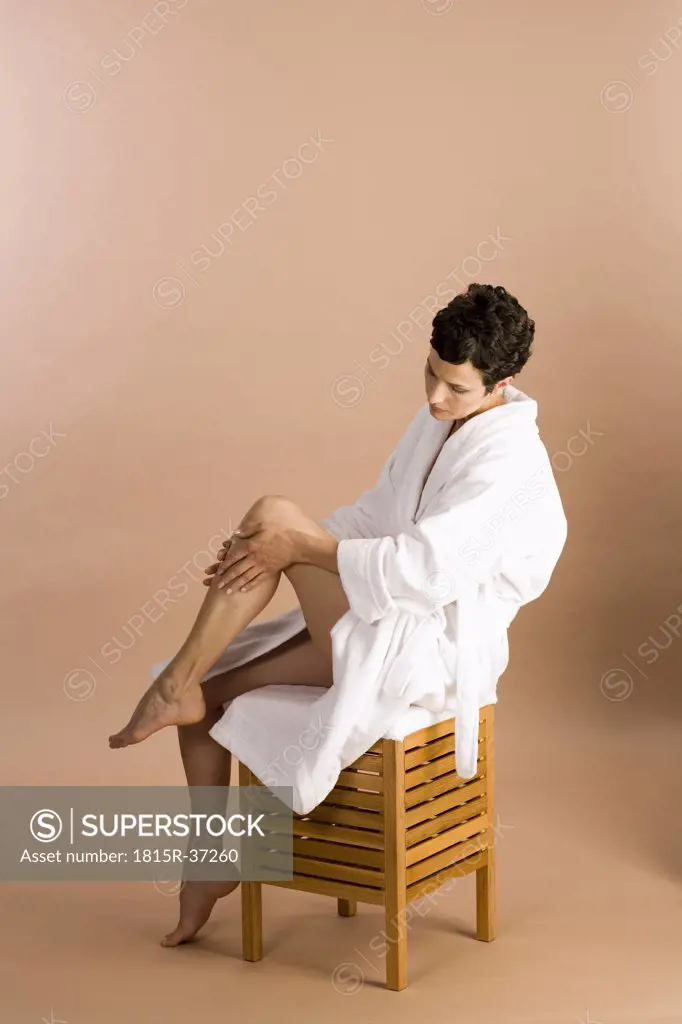 Woman applying cream on legs, portrait
