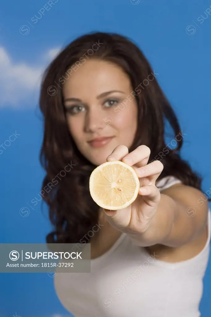 Portrait of a young woman holding half of lemon