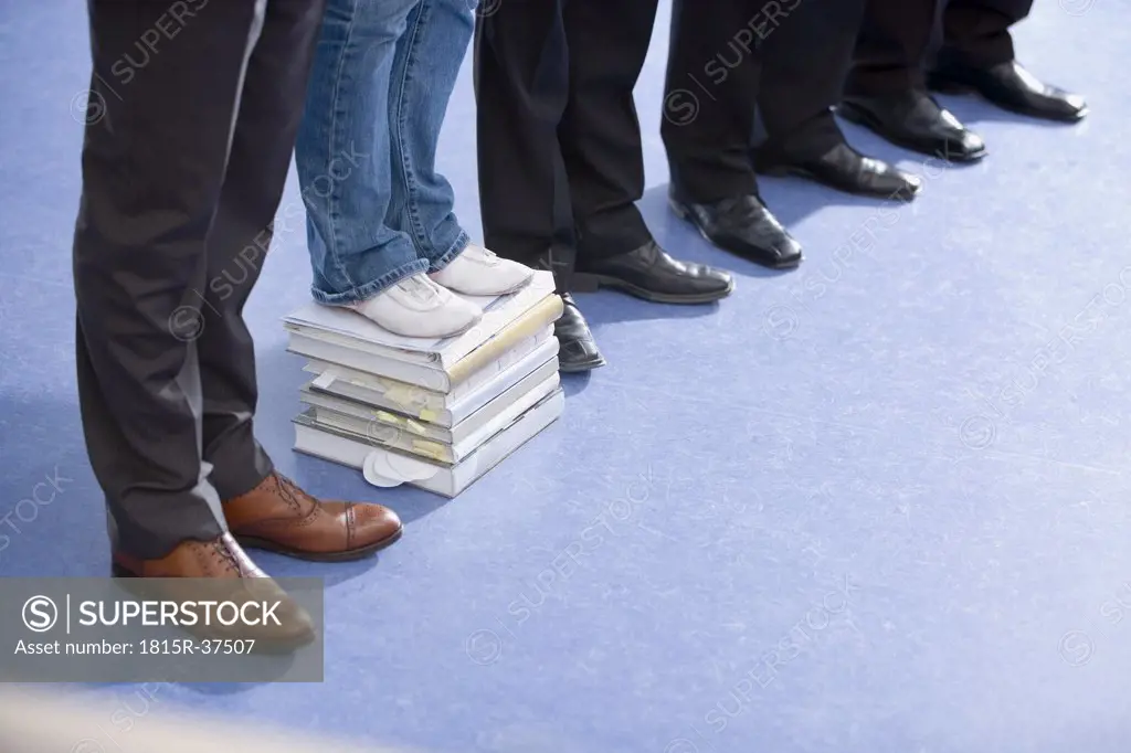 Five persons, on of them standing on stack of books, low section