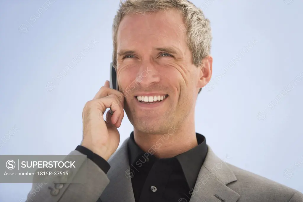 Business man using mobile phone, smiling, portrait