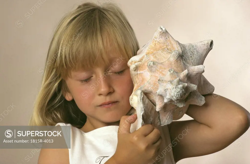 Girl listening to sea shell, close up