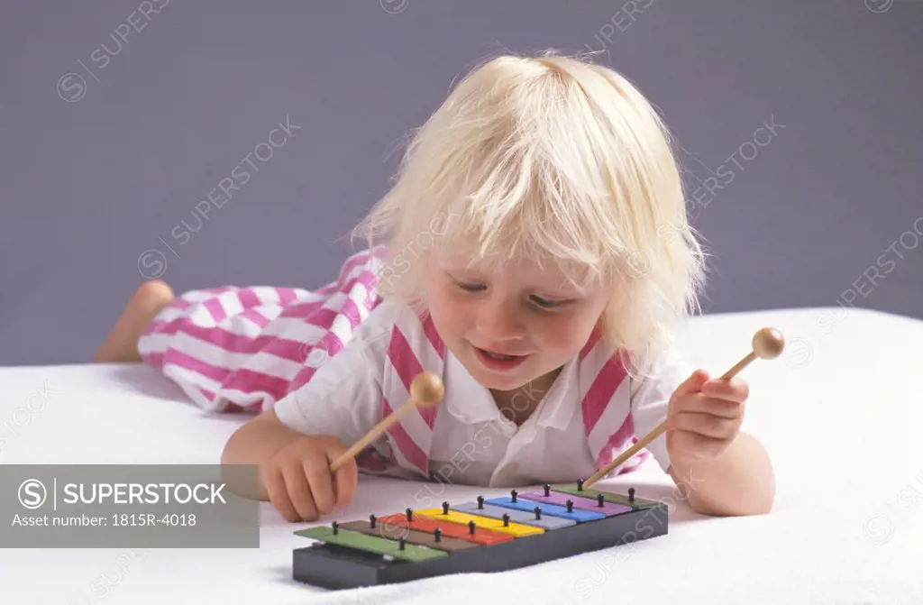 little child trying to play xylophone