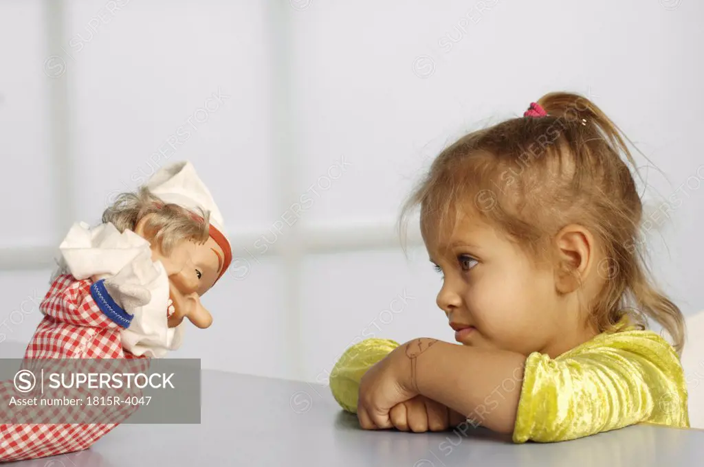 Girl (3-5) looking at glove puppet