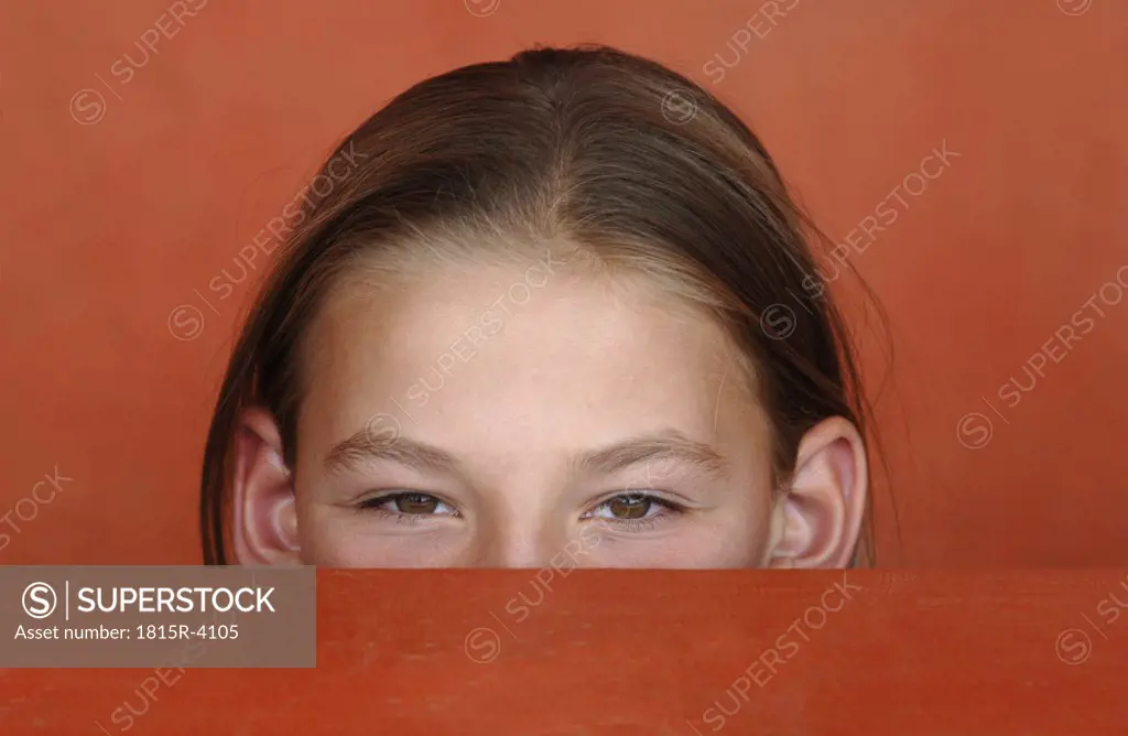 Girl (8-9) looking over red table, portrait