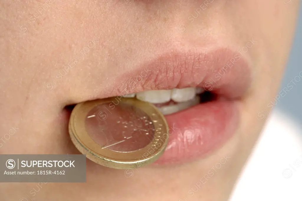 Child with coin between teeth, close-up
