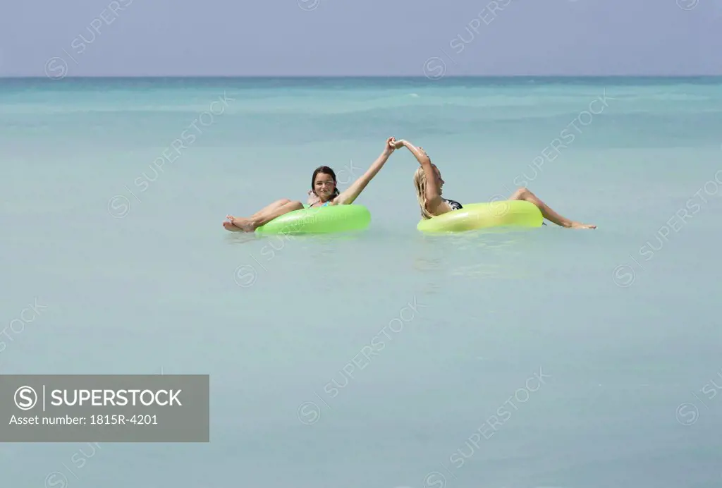 Two girls with tire in water
