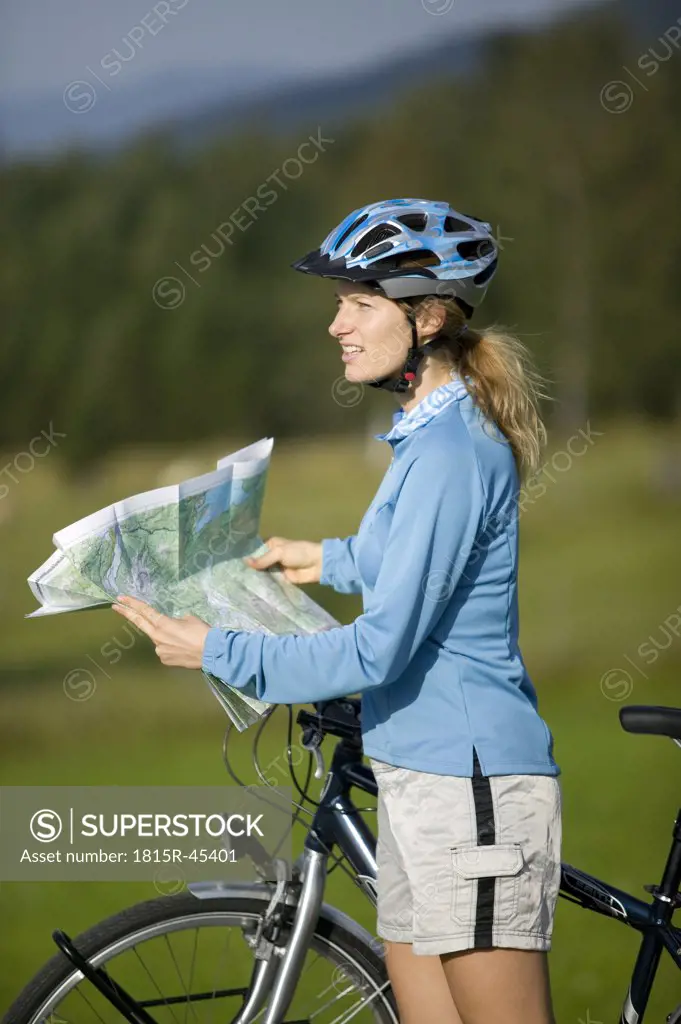 Germany, Bavaria, Mittenwald, Woman with mountain bike holding map