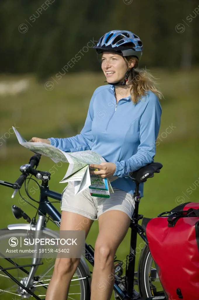Germany, Bavaria, Mittenwald, Woman leaning against mountain bike, holding map