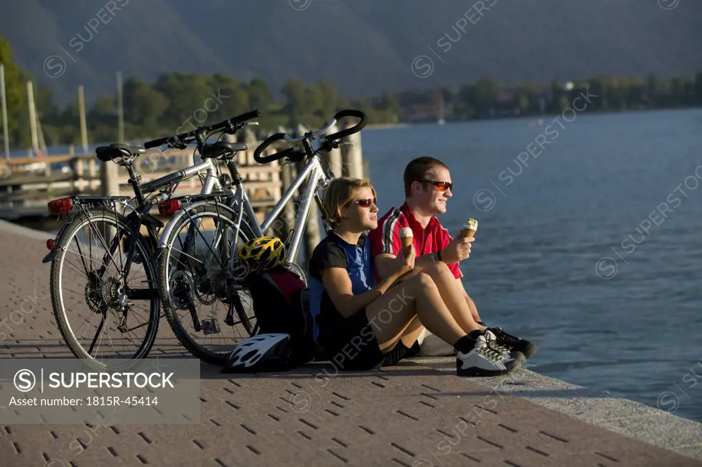 Germany, Bavaria, Tegernsee, Couple with mountain bikes eating ice cream