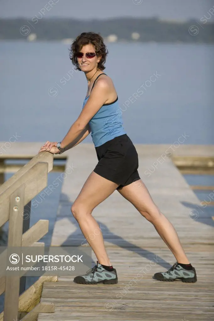 Germany Bavaria, Tutzung, Woman on landing stage stretching leg