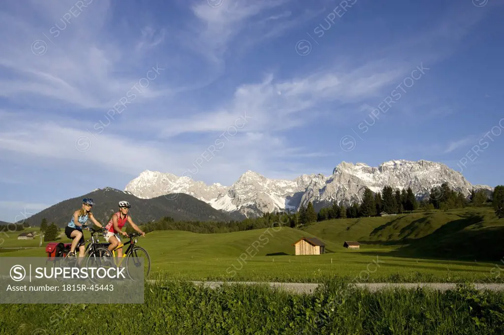 Germany, Bavaria, Mittenwald, Two women mountain biking across highway