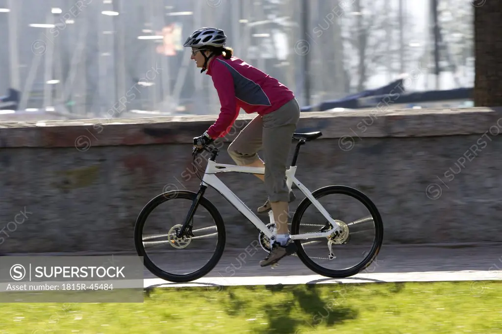 Italy, Trento, Riva del Garda, Female mountainbiker riding across pier