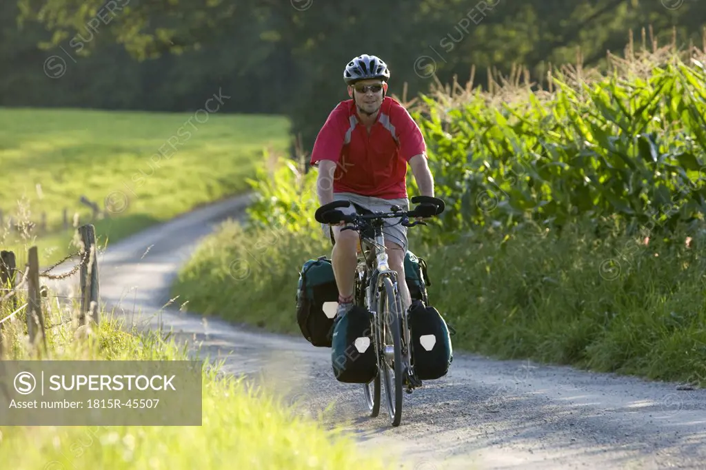 Germany, Bavaria, Oberland, Man mountainbiking across farm track