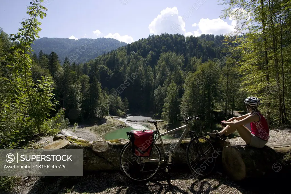 Germany, Bavaria, Lake Sylvenstein, Woman with mountain bike taking a break
